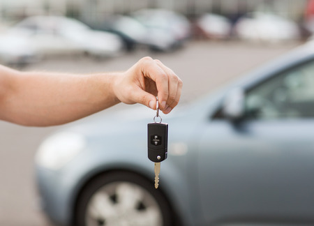 transportation and ownership concept - man with car key outsideの写真素材