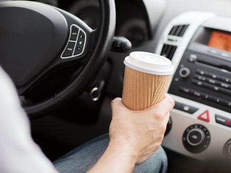 transportation and vehicle concept - man drinking coffee while driving the carの写真素材