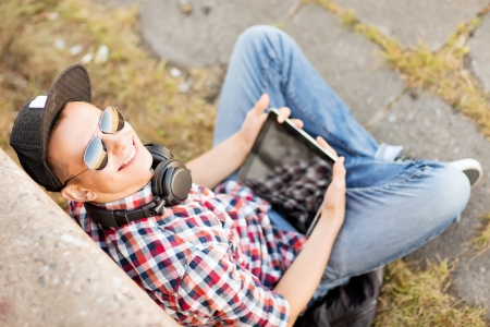 summer holidays, teenage and technology concept - teenager with headphones and tablet pc outsideの写真素材