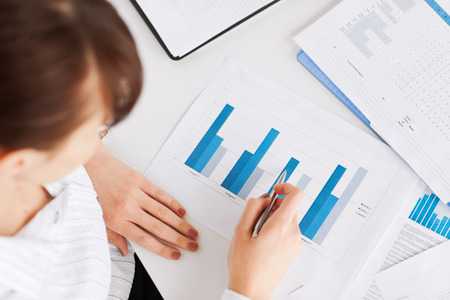 business, office, school and education concept - woman hand with charts and papersの写真素材