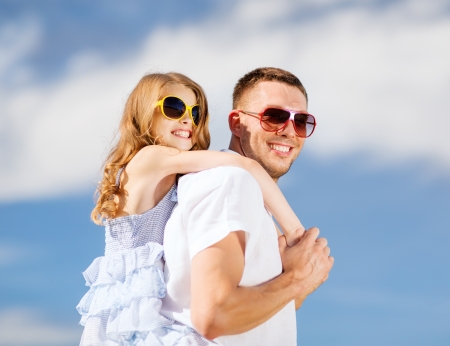 summer holidays, children and people concept - happy father and child in sunglasses over blue skyの写真素材