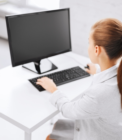 business, office, school and education concept - businesswoman on computer with blank screen in officeの写真素材