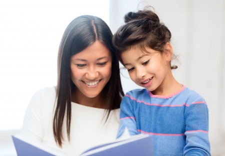 family, children, education, school and happy people concept - mother and daughter with bookの写真素材