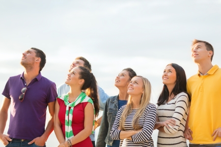 summer, holidays, vacation, happy people concept - group of friends looking up on the beachの写真素材