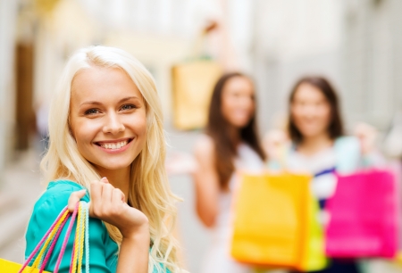 shopping and tourism concept - beautiful girls with shopping bags in ctiyの写真素材