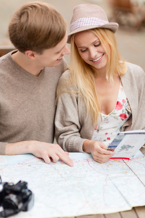 summer holidays, dating, city break and tourism concept - couple with map, camera and travellers guideの写真素材