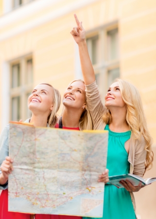 holidays and tourism concept - beautiful blonde women with tourist map in the cityの写真素材