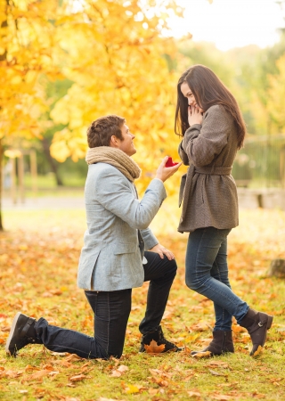 holidays, love, couple, relationship and dating concept - kneeled man proposing to a woman in the autumn parkの写真素材