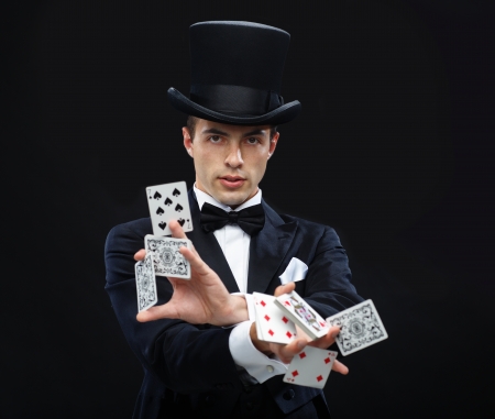 magic, performance, circus, gambling, casino, poker, show concept - magician in top hat showing trick with playing cardsの写真素材