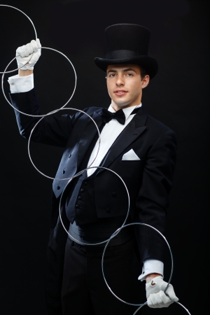 magic, performance, circus, show concept - magician in top hat showing trick with linking ringsの写真素材