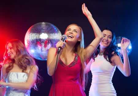 party, "new year", celebration, friends, bachelorette party, birthday concept - three women in evening dresses dancing and singing karaokeの写真素材