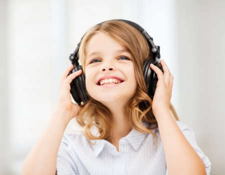 home, leisure, new technology and music concept - smiling little girl with headphones at homeの写真素材