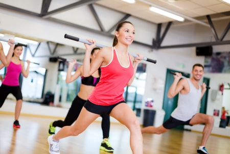 fitness, sport, training, gym and lifestyle concept - group of smiling people working out with barbells in the gymの写真素材