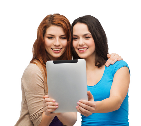 technology, friendship and people concept - two smiling teenagers taking picture with tablet pc cameraの写真素材