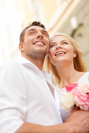 summer holidays, love, relationship and dating concept - couple with bouquet of flowers in the cityの写真素材