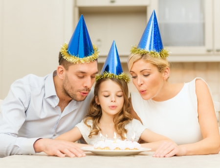celebration, family, holidays and birthday concept - happy family in blue hats with cakeの写真素材