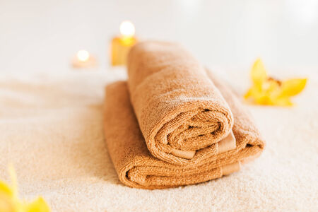 spa, health and beauty concept - closeup of towels, flowers and candlesの写真素材