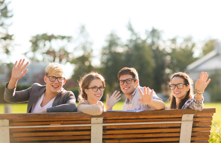summer holidays, education, campus and teenage concept - group of students or teenagers in eyeglasses waving handsの写真素材
