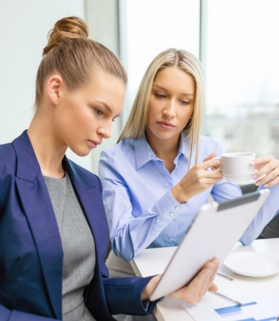 business, technology and office concept - serious businesswomen with tablet pc computers having discussion in officeの写真素材