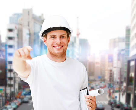 building, developing, construction and architecture concept - male architect in helmet pointing at youの写真素材