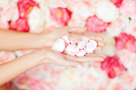 health and beauty concept - close up of womans cupped hands with flower petalsの写真素材