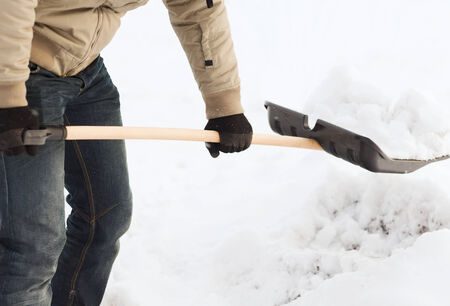 winter and cleaning concept - closeup of man shoveling snow from drivewayの写真素材