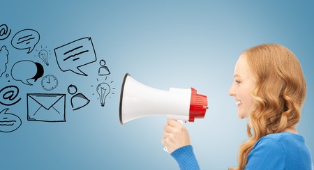 communication concept - woman with megaphone over blue backgroundの写真素材