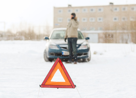 transportation, winter and vehicle concept - closeup of man with broken car, warning triangle and...