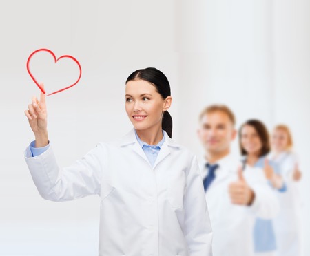 healthcare, medicine and technology concept - smiling female doctor pointing to heartの写真素材