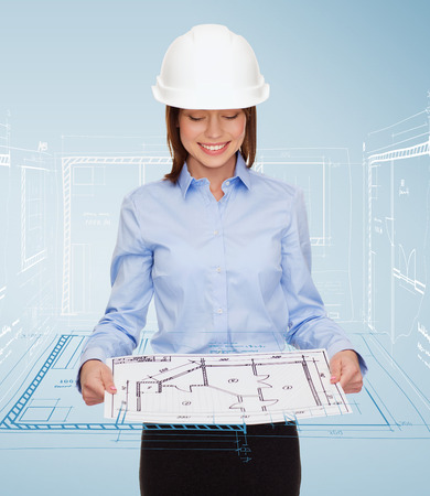 building, developing, consrtuction and architecture concept - smiling businesswoman in white helmet looking at blueprintの写真素材