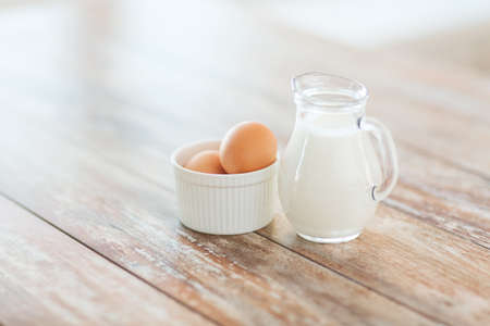 cooking and food concept - close up of jugful of milk and eggs in a bowlの写真素材