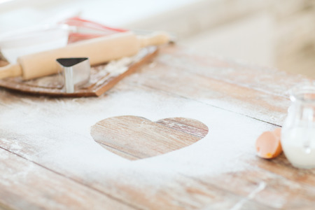 cooking and love concept - close up of heart of flour on wooden table at homeの写真素材