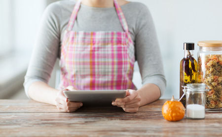 cooking, technology and home concept - closeup of woman reading recipe from tablet pc computerの写真素材