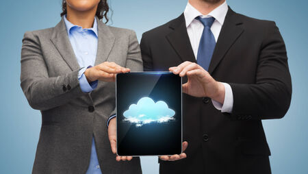 business, technology and internet concept - businessman and businesswoman with cloud on tablet pc screenの写真素材