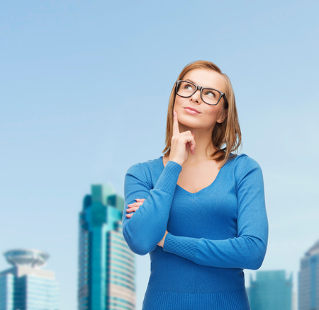 happiness and people concept - happy smiling young woman in black eyeglasses dreamingの写真素材
