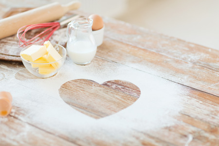 cooking and love concept - close up of heart of flour on wooden table at homeの写真素材
