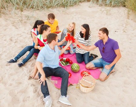 summer, holidays, vacation, music, happy people concept - group of friends celebrating birthday on beachの写真素材