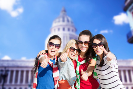 summer, holidays, vacation, happy people concept - beautiful teenage girls or young women showing thumbs upの写真素材