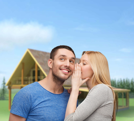 relationships, love and couple concept - smiling girlfriend telling boyfriend secretの写真素材