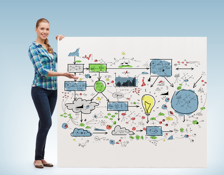 happiness, advertising and people concept - smiling young woman pointing hand to big plan on boardの写真素材