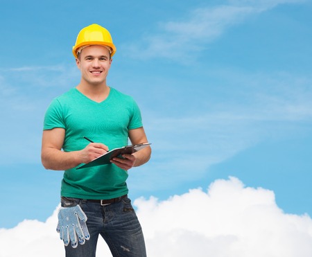 repair, construction and maintenance concept - smiling man in helmet with clipboard