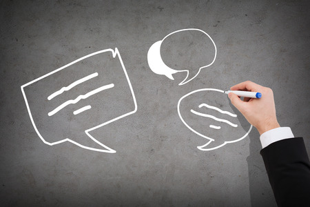 business and communication concept - close up of businessman drawing message bubbles on concrete wallの写真素材