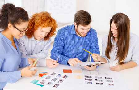 business, office, architecture and startup concept - smiling creative team with color samples and blueprint at officeの写真素材