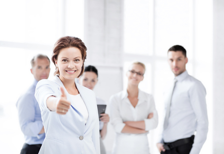 business concept - attractive businesswoman with team in office showing thumbs upの写真素材