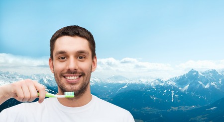 health and beauty concept - smiling young man with toothbrush