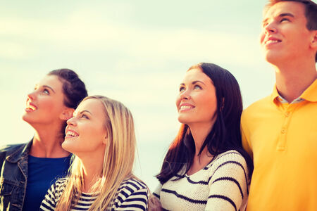 summer, holidays, vacation, happy people concept - group of friends looking up on the beach