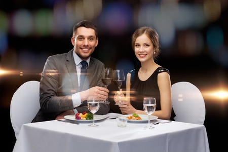 restaurant, couple and holiday concept - smiling couple eating main course with red wine at restaurantの写真素材