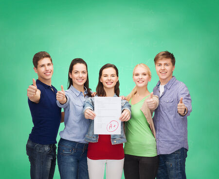 education and people concept - group of smiling students standing and showing test and thumbs upの写真素材