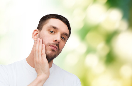 health and beauty concept - beautiful calm man touching his faceの写真素材