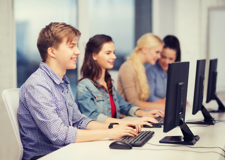 education, technology and internet concept - students looking at computer monitor at school